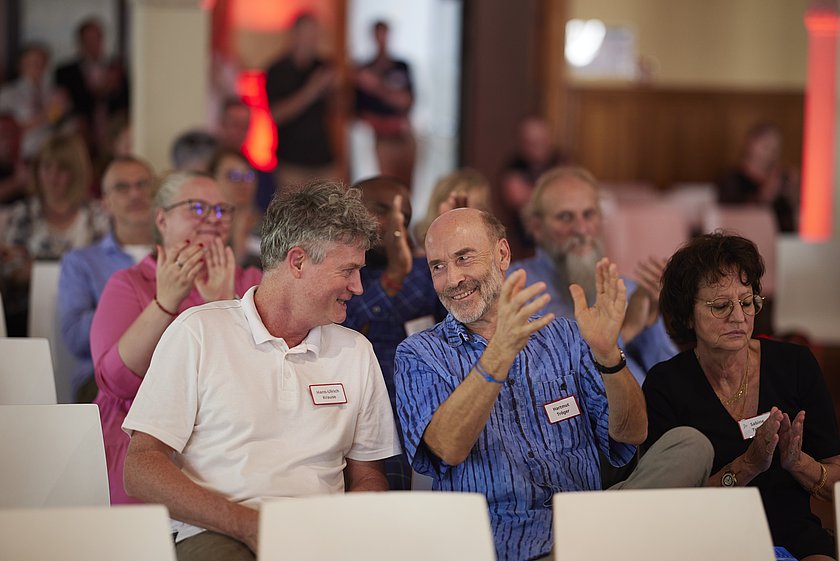 Teilnehmer:innen des Events im Publikum, aufmerksam den Vorträgen lauschend.