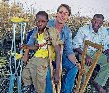 Eine Gruppe von Menschen steht mit landwirtschaftlichen Geräten in einem Feld und lächelt in die Kamera.