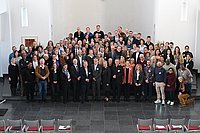 Ein großes Gruppenfoto, aufgenommen in einer Aula oder einem Konferenzraum, mit mehreren Reihen von Personen.