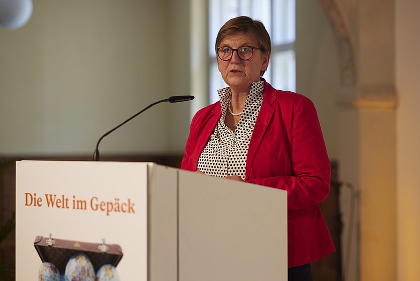 Eine Frau in rotem Blazer spricht an einem Rednerpult.