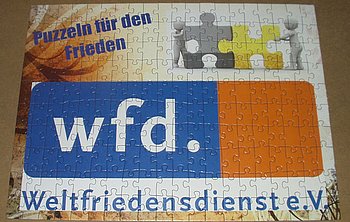 Ein Ausschnitt des Logos des Weltfriedensdienstes (wfd) auf einem Stoffstück.