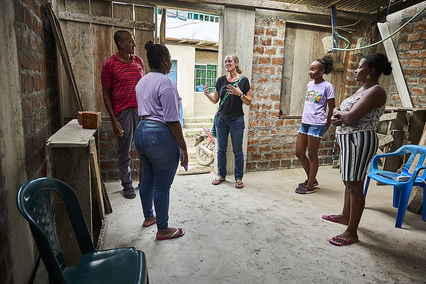 Fünf Personen stehen auf Betonboden umgeben von geziegelten Mauern. In der Mitte der Runde steht Ulrike Purrer. 
