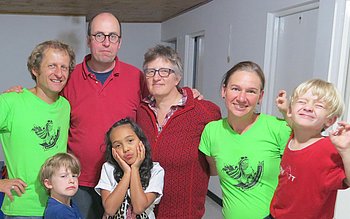 Eine Gruppe von Menschen, darunter Erwachsene und Kinder, posiert gemeinsam in einem hellen Raum.