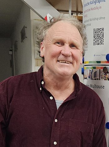 Fritz Ritzmann trägt ein dunkelrotes Hemd. Er lächelt in die Kamera.