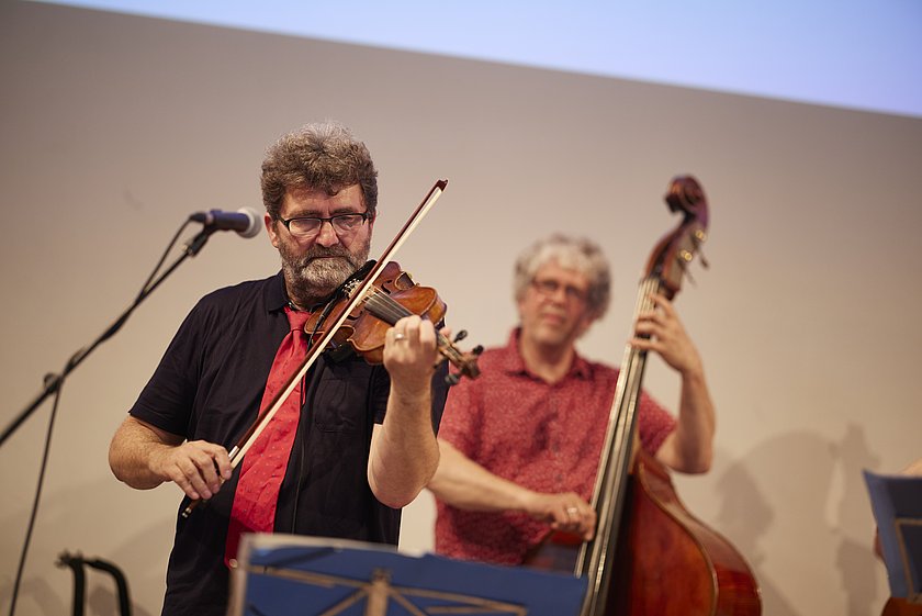 Musiker spielen auf der Bühne ein Kontrabass und eine Geige bei einer kulturellen Darbietung.