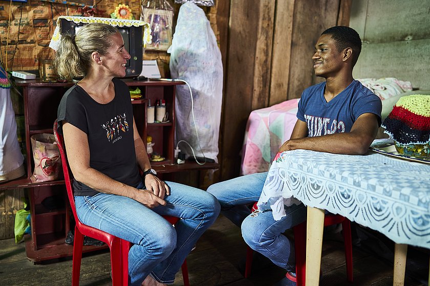 Ulrike Purrer und Jailer Daniel Cortés Hortado sitzen sich gegenüber. Beide lächeln. 