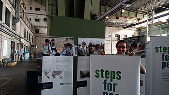 Eine Ausstellungsszene mit Stellwänden, auf denen der Schriftzug "Steps for Peace" zu lesen ist.