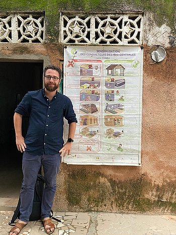 Gabriel Odin Ein Mann steht vor einem Plakat, das an eine Hauswand geheftet ist.