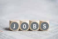 Holzwürfel mit dem Schriftzug 'JOBS', die auf einem Tisch liegen.